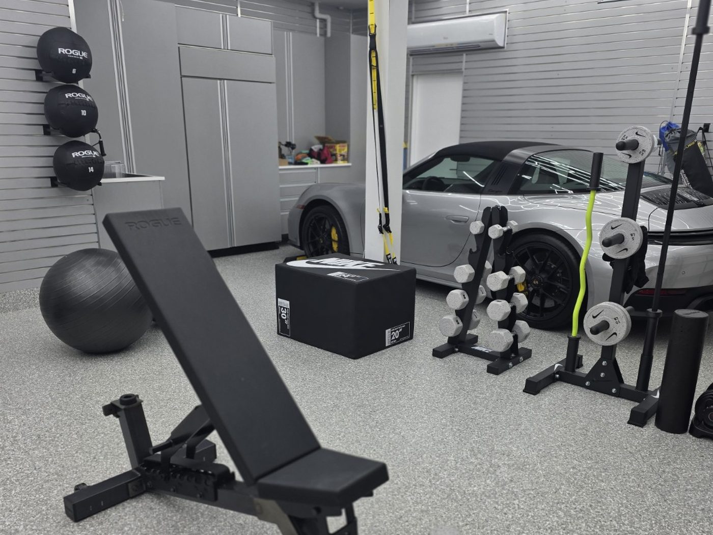 Two-car garage gym with hexagon ceiling lighting and slatwall storage