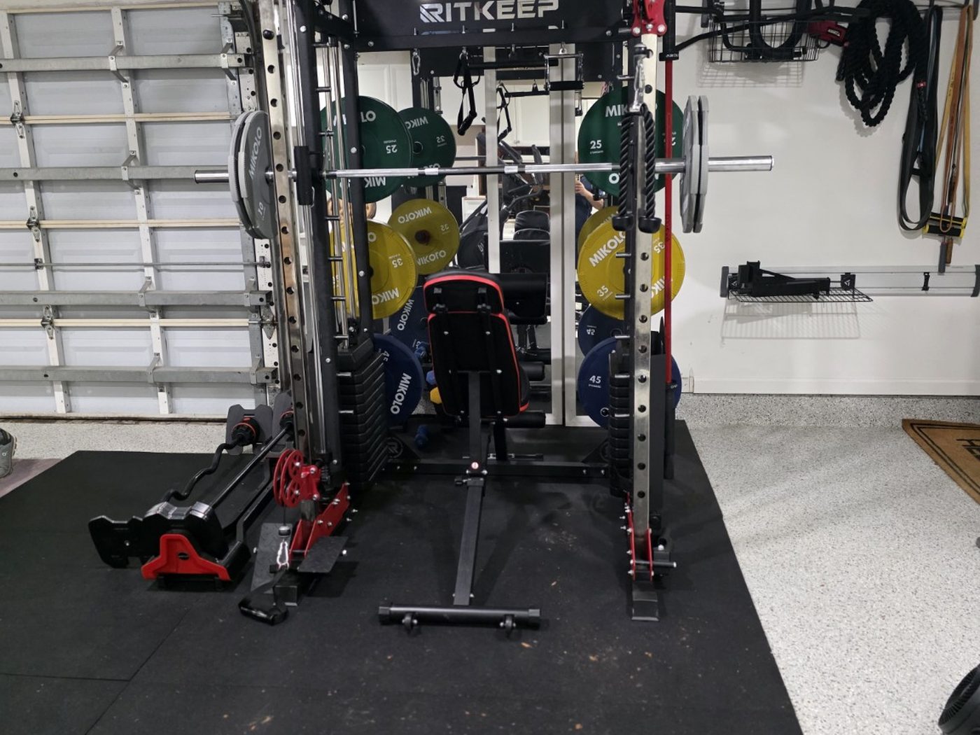 All-in-one functional trainer on a black rubber platform in a single garage bay