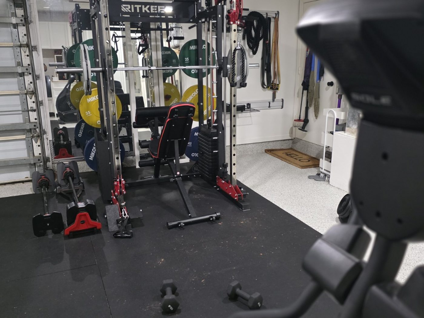 The training zone seen past the cardio machine, showing how the rubber platform separates the gym from the rest of the garage